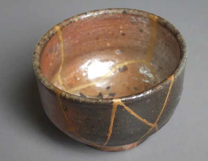 Een keramieken kom waarvan de breuken met goud zijn hersteld (kintsugi)